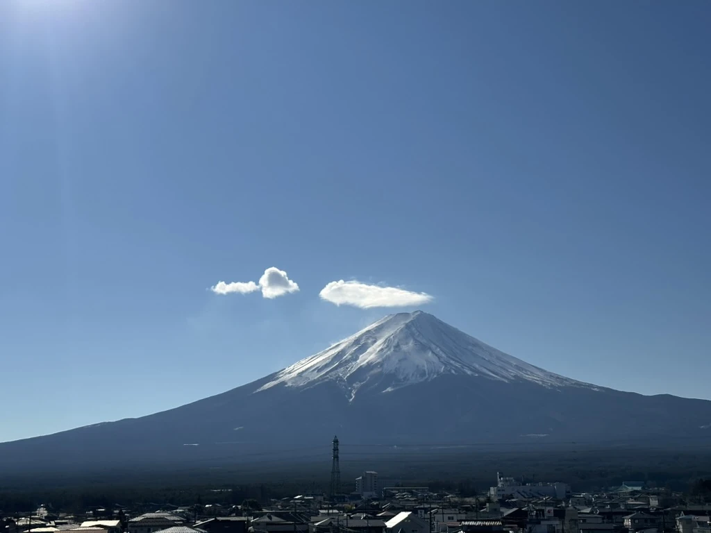Snow-covered Mount Fuji above town rooftops beneath a clear blue sky.